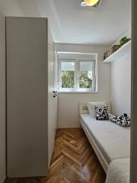 Manja opremljena spavaća soba sa krevetom i ormarom. - image 15
