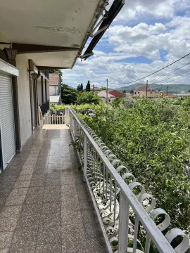 Long covered balcony with a metal railing and a view of greenery and surrounding houses. - image 5
