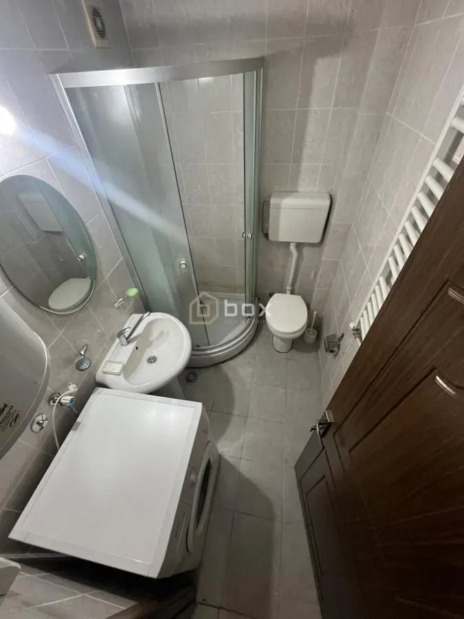 Smaller bathroom with a shower cabin, washbasin, toilet, and washing machine.