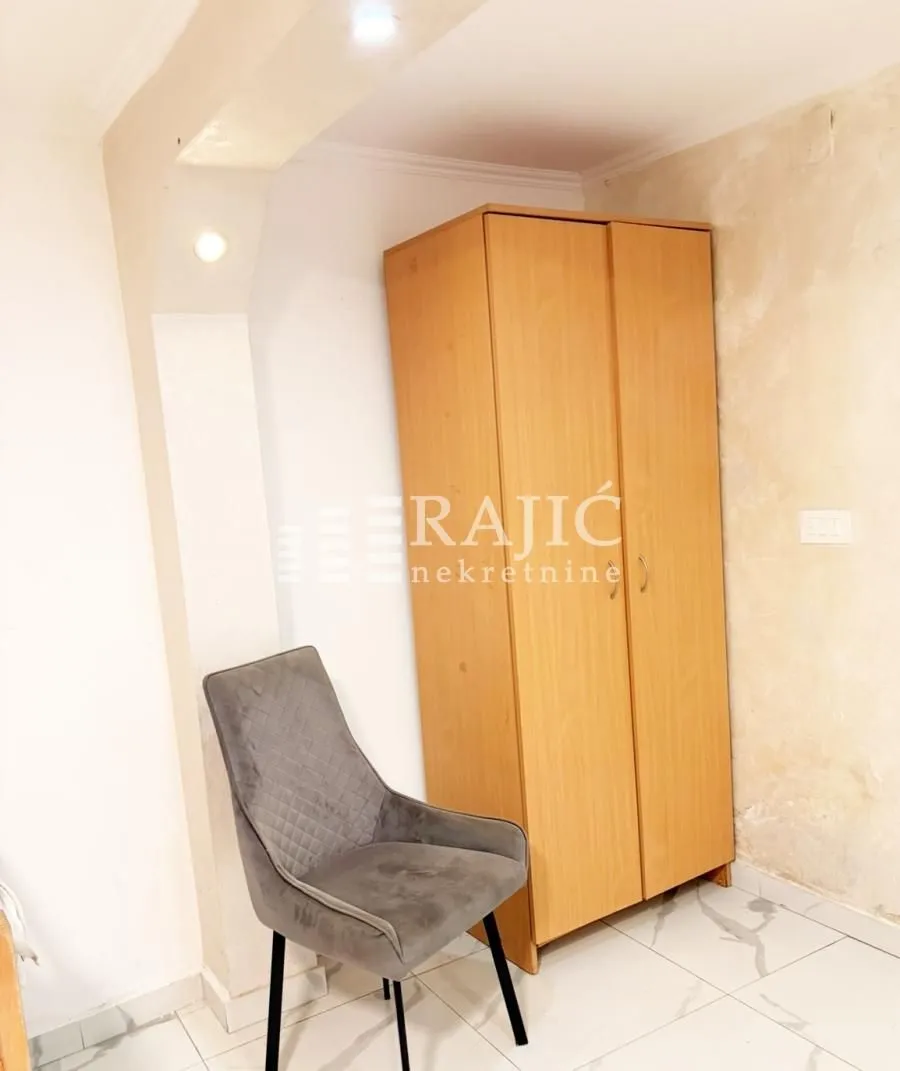 Small room with a wardrobe and a grey armchair.