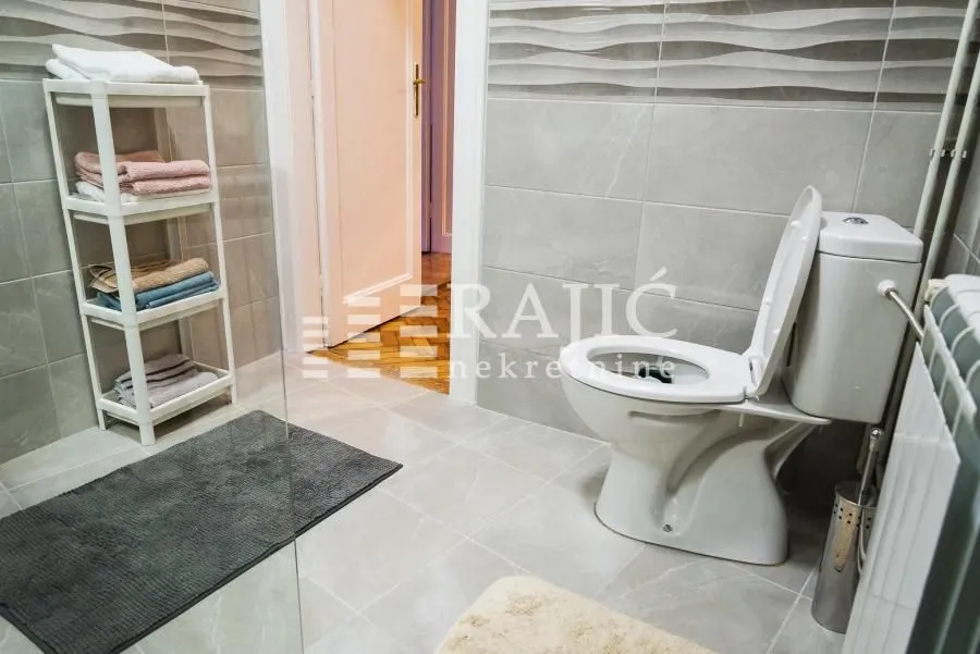 Modernly equipped bathroom with sanitary fixtures and a towel shelf.