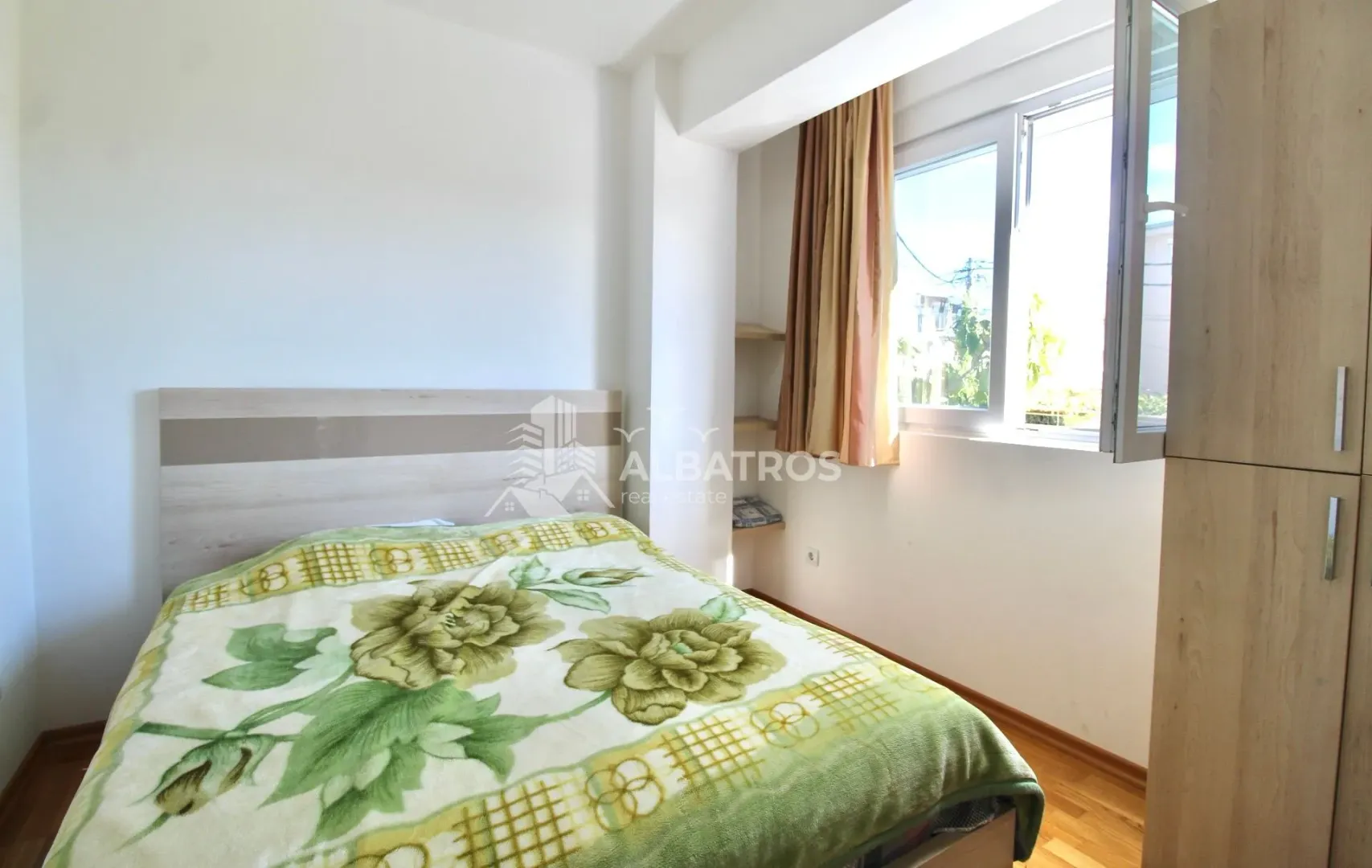 Furnished bedroom with a double bed, window, and wardrobe.
