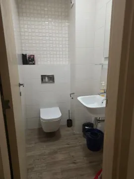 Small bathroom with white tiles, a washbasin and a toilet bowl. - image 12