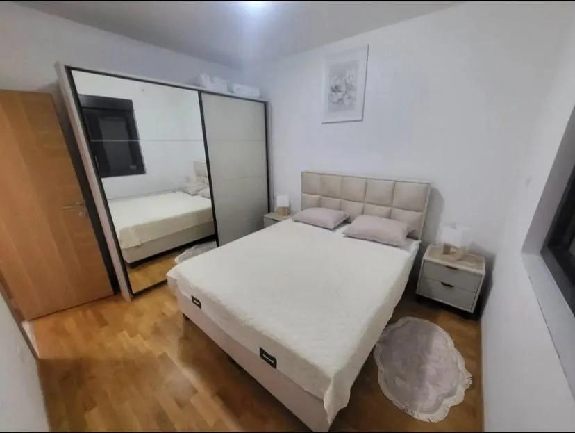 Furnished bedroom with a double bed and a large mirrored wardrobe.