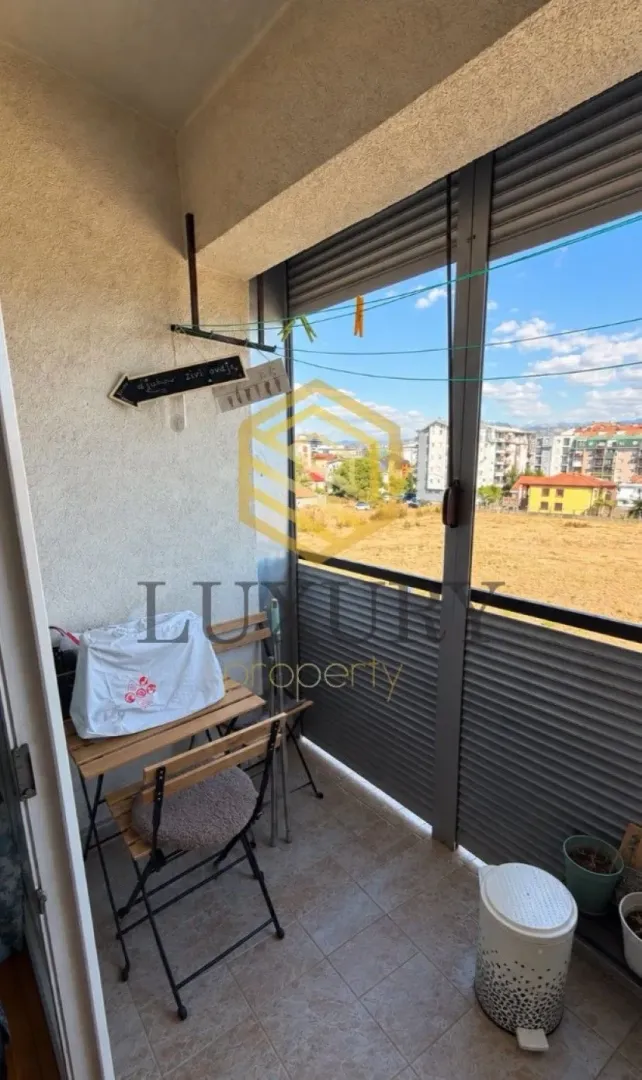 Smaller enclosed balcony with a table, chairs, and city view.