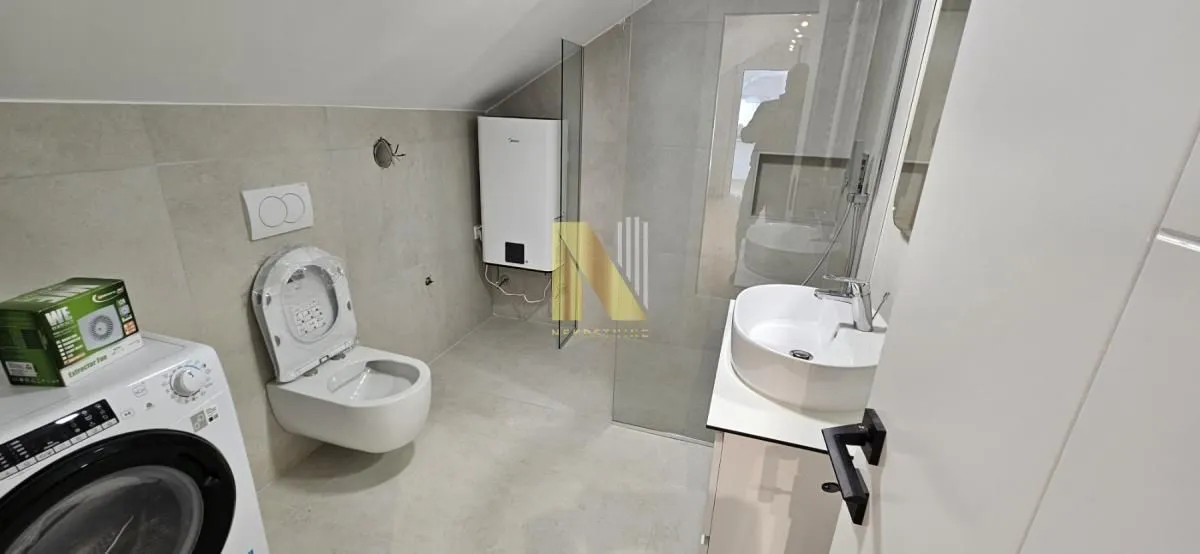 Novoopremljeno kupatilo sa sanitarijama, tuš kabinom i mašinom za veš.