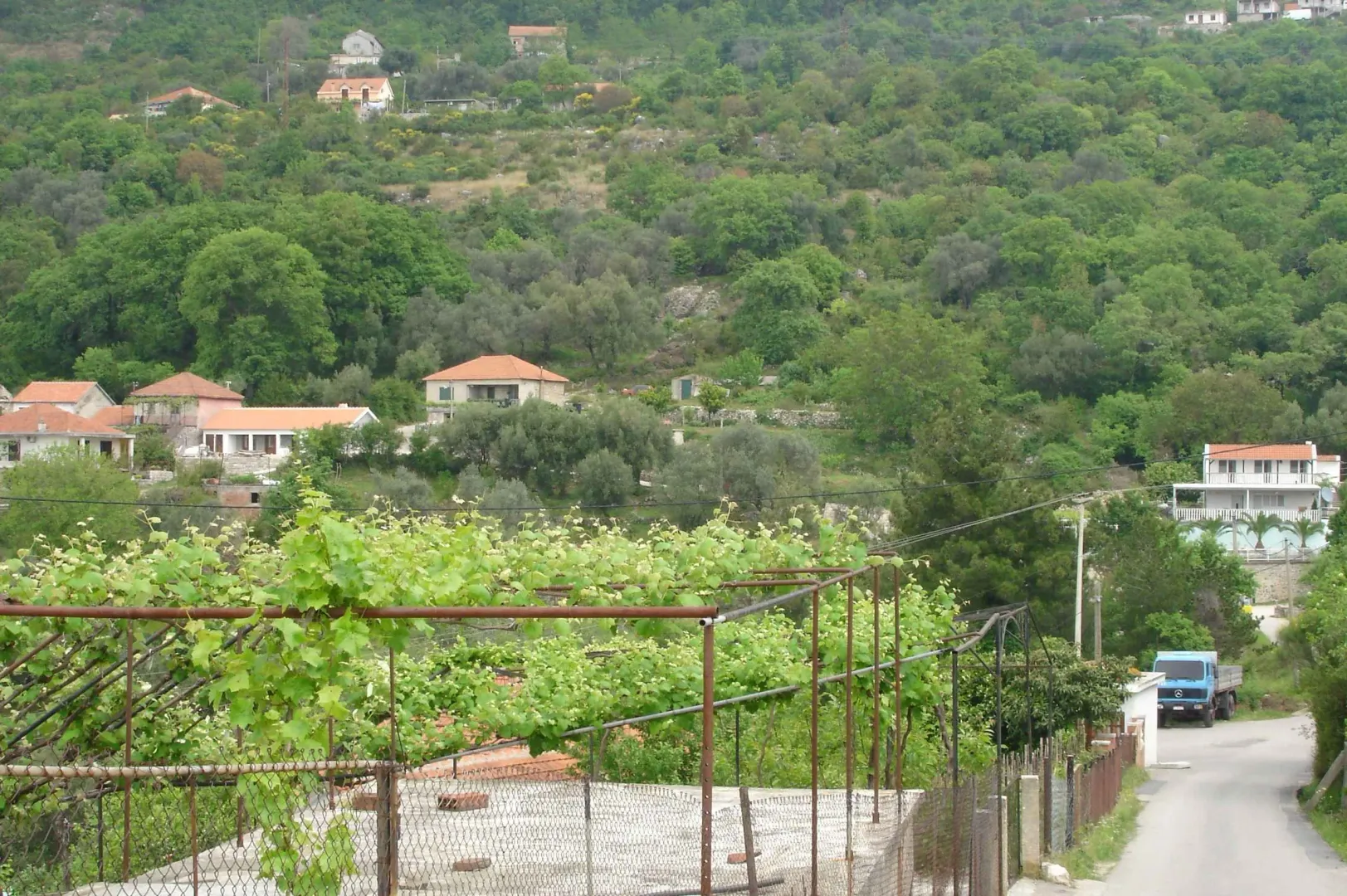 Pogled na kuće i zeleno brdo u mirnom okruženju.