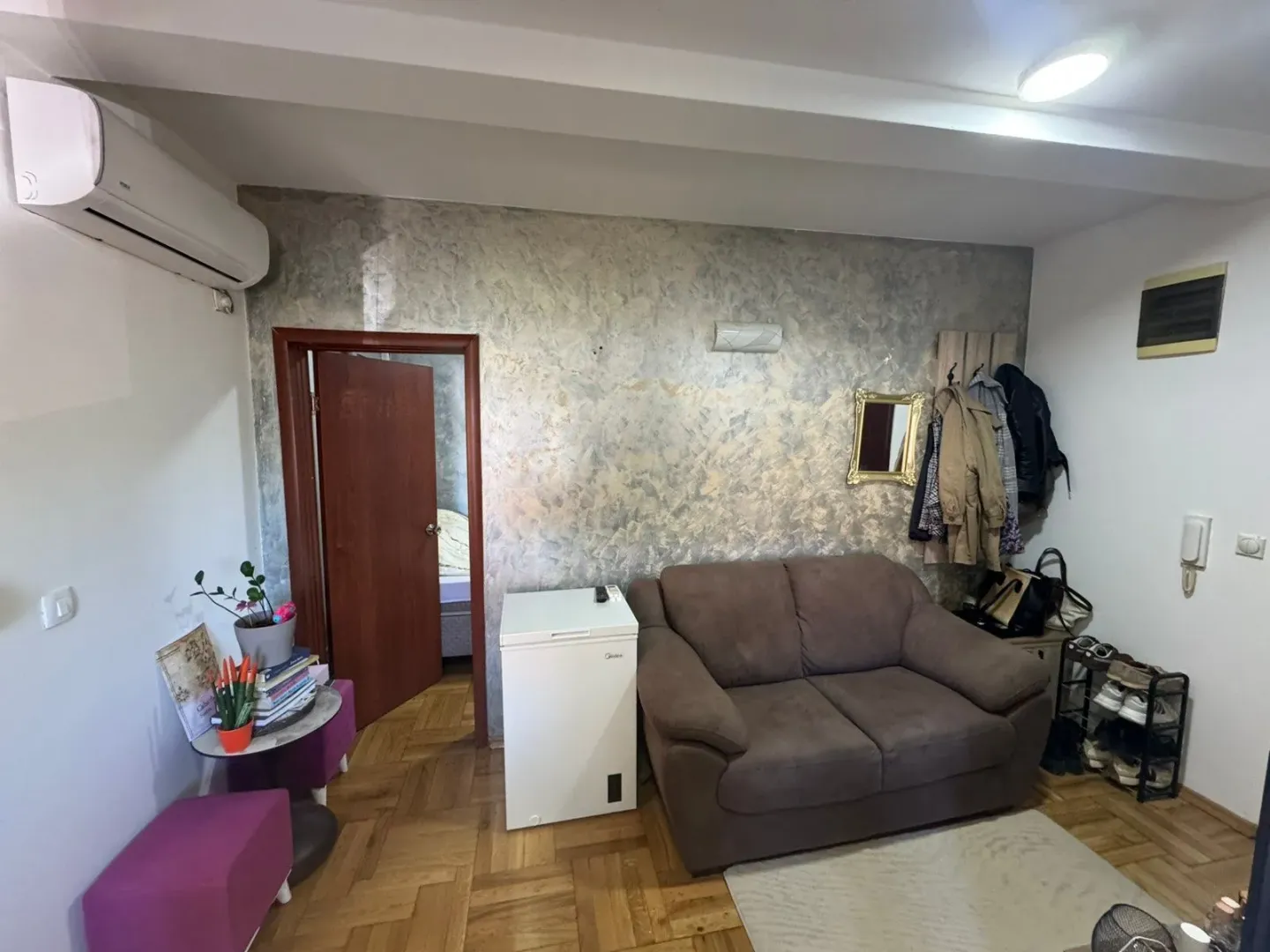 Living room with a sofa, air conditioning, and parquet flooring.