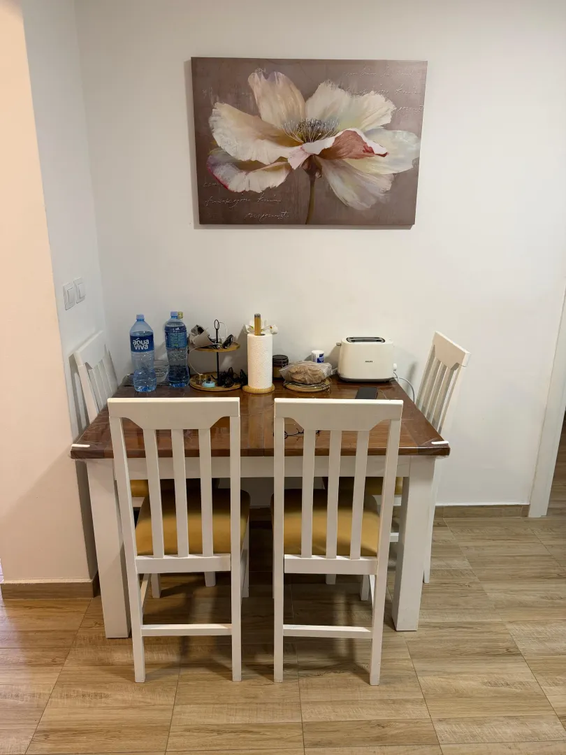 Trpezarija sa drvenim stolom i bijelim stolicama.