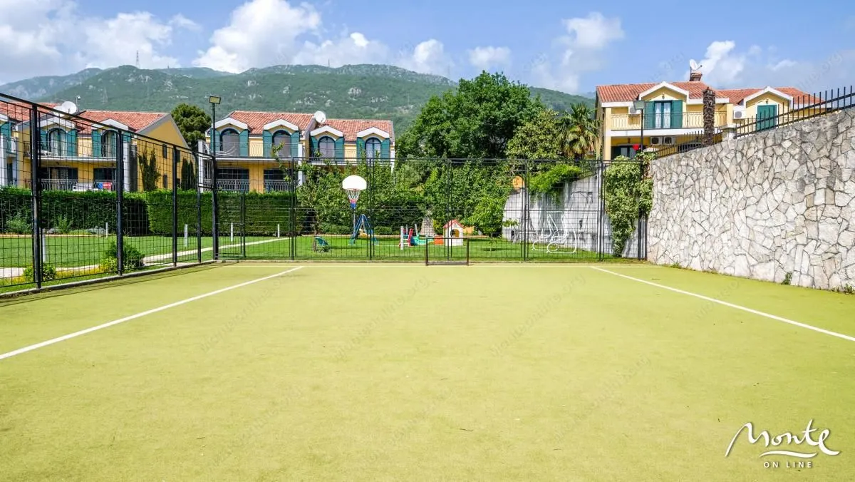 Pogled na sportski teren i zelenu površinu ispred zgrada.