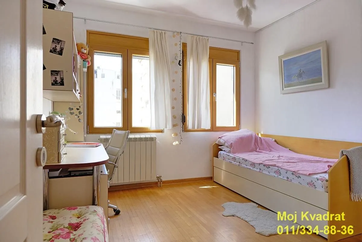 Dečja soba sa krevetom, radnim stolom i drvenom stolarijom.