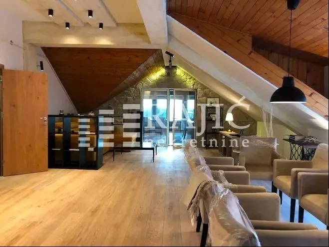 Spacious attic living room with wooden ceiling and hardwood flooring.