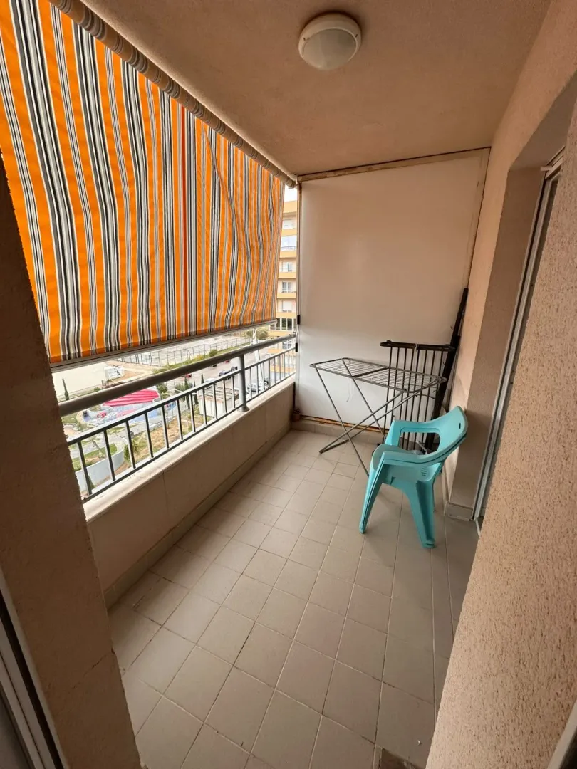 Covered balcony with an awning, chair, and drying rack.