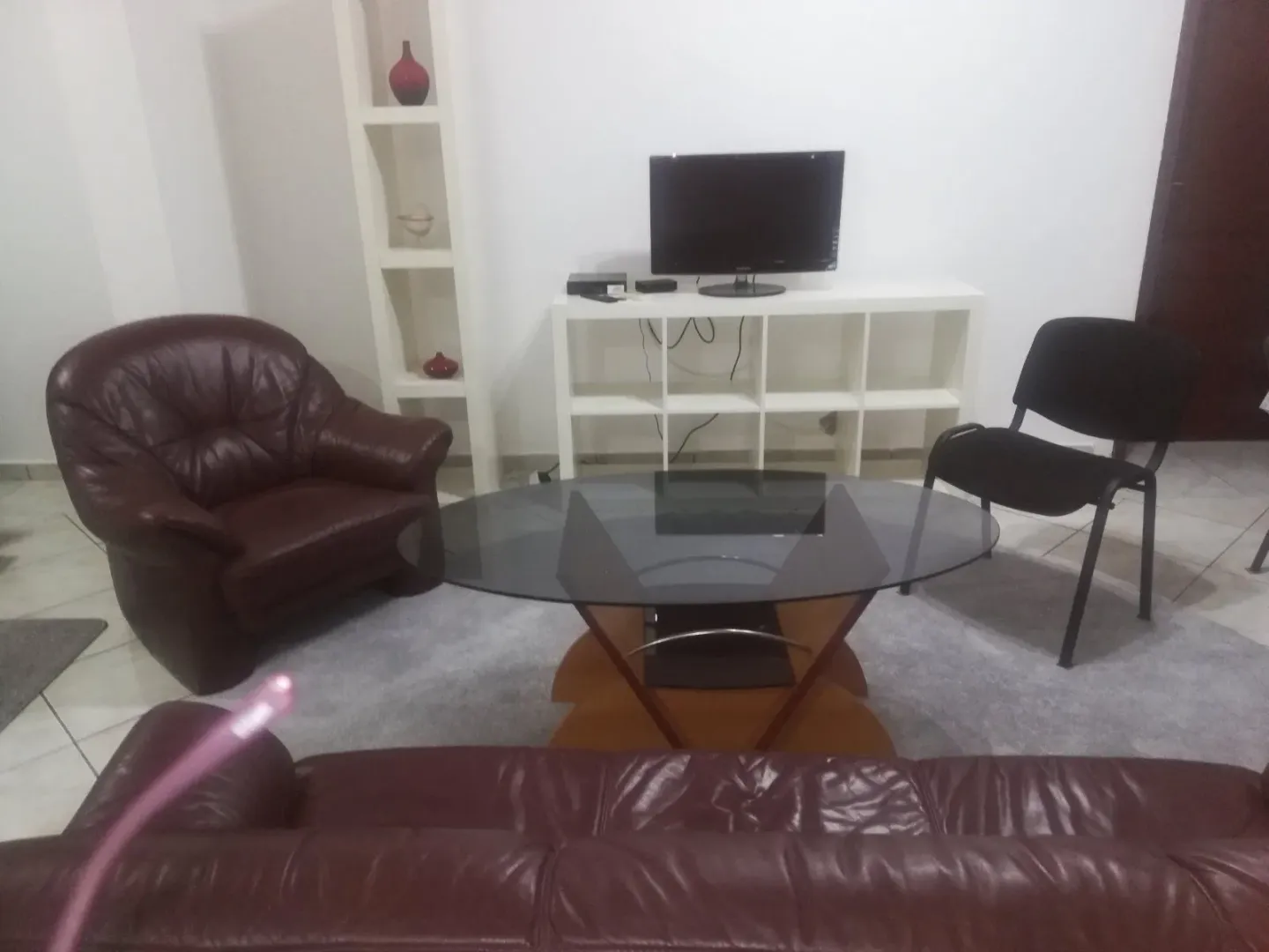 Living room with leather furniture, a glass coffee table, and a TV.