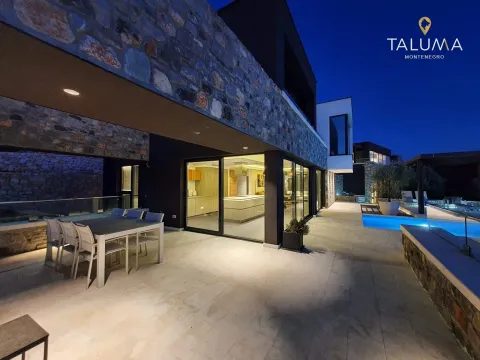 Exterior of the villa at night with a dining table, terrace, and swimming pool. - image 3