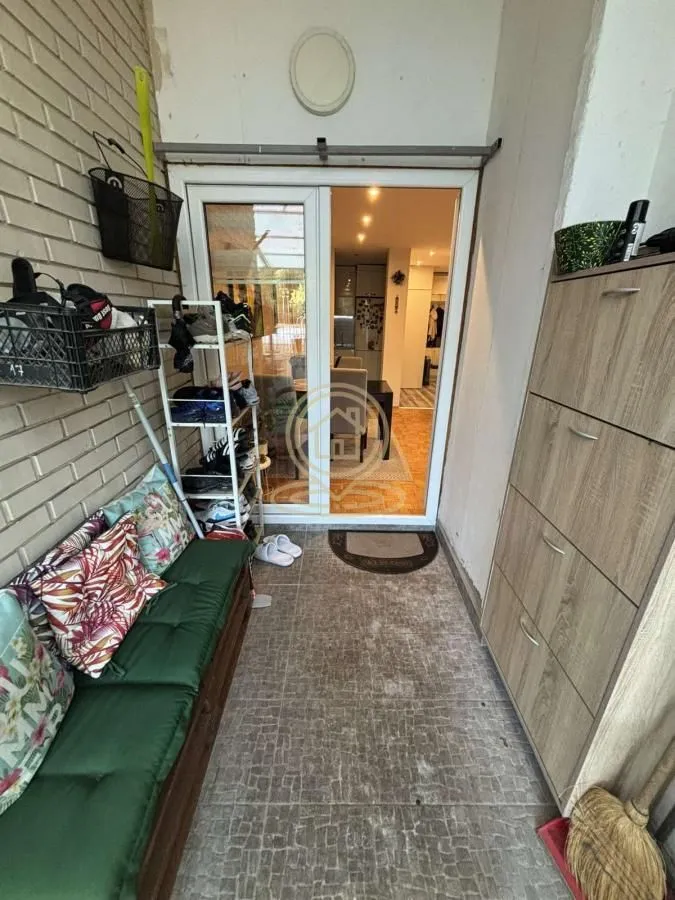 Natkriveni balkon opremljen klupom za sedenje, policama za obuću i ormarićem.