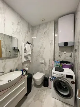 Bright bathroom with a washing machine and modern fixtures. - image 4