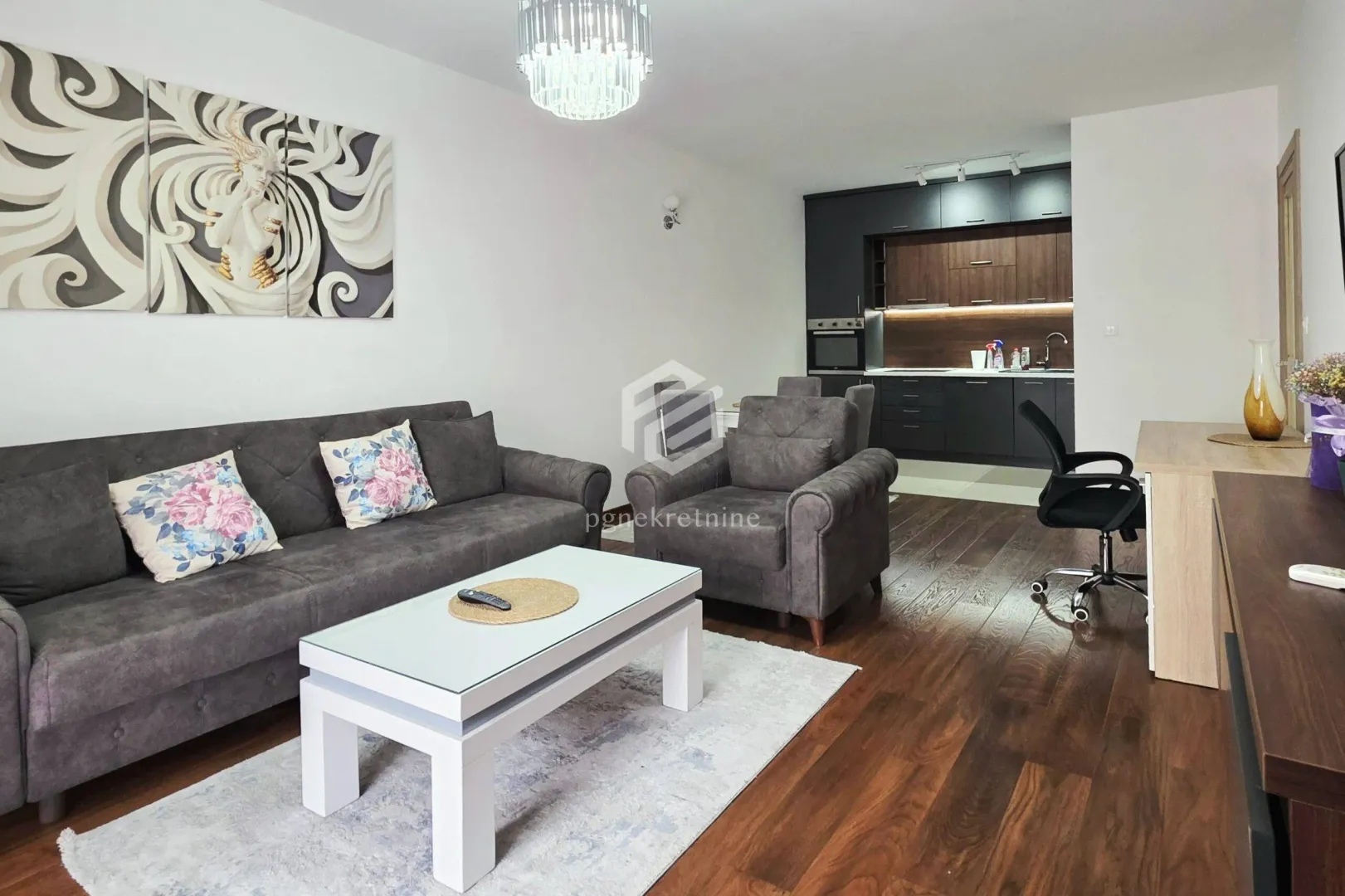Living room with sofa, coffee table and a view of the kitchen in the background.