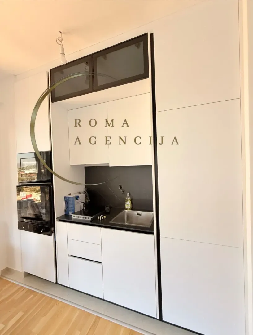 Modern white kitchen with black elements and built-in appliances.