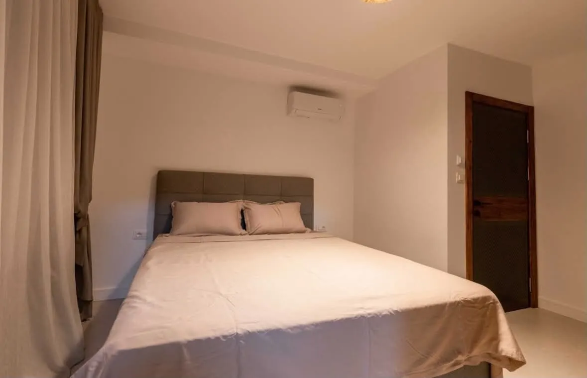 Bedroom with a double bed, air conditioning unit, and a door.