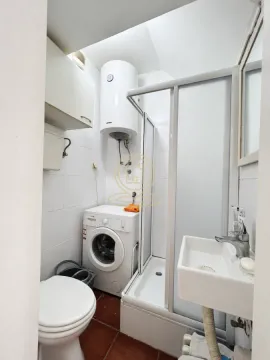 Smaller bathroom with a shower cabin, washbasin, toilet, and washing machine. - image 7