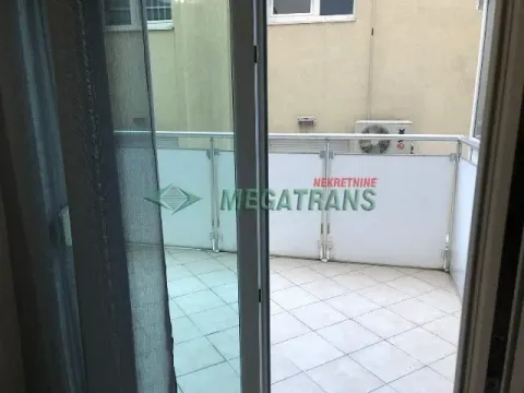 Pogled na popločanu terasu sa staklenom ogradom kroz balkonska vrata. - image 9