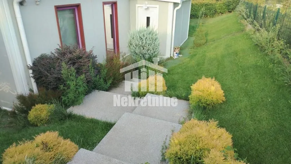 A view of part of the yard and the entrance to the house with a landscaped lawn.
