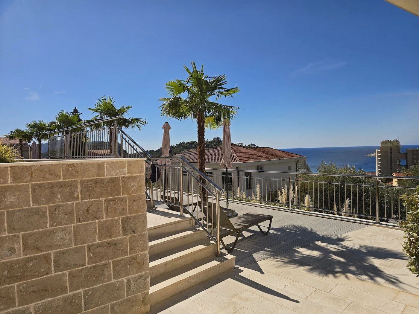 Spacious terrace with a sea view and palm trees.