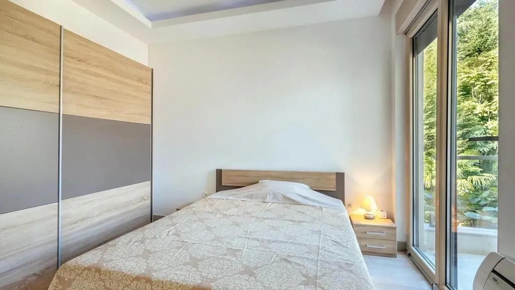 Svijetla spavaća soba sa bračnim krevetom, garderoberom i velikim kliznim vratima.