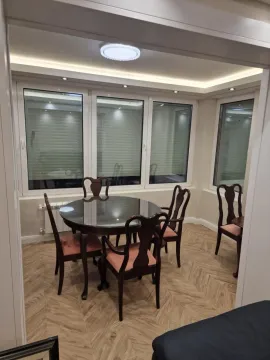 Trpezarija sa okruglim stolom i tamnim drvenim stolicama pored velikih prozora. - image 6