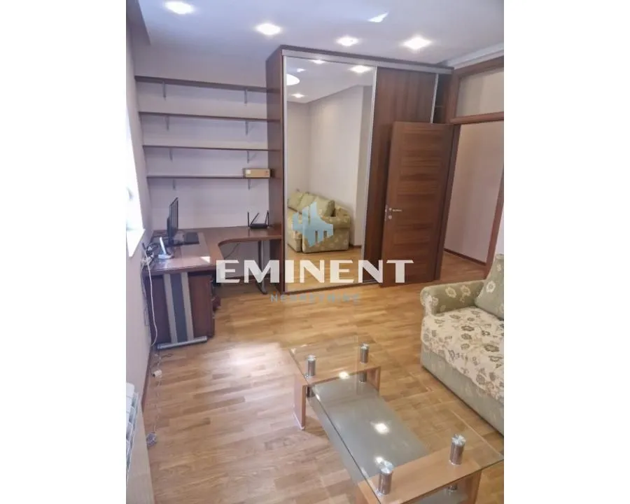 Living room with a desk, built-in wardrobe, and seating furniture.