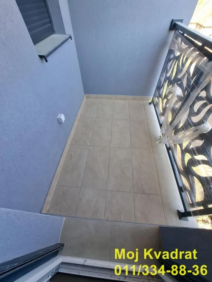 Manji popločani balkon sa metalnom ogradom.