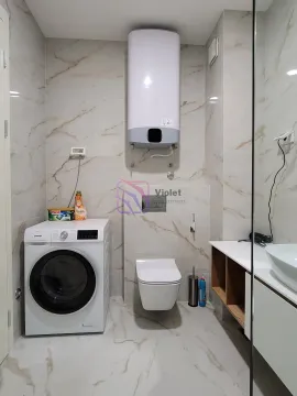 Modern bathroom equipped with a washing machine, toilet, and sink. - image 12
