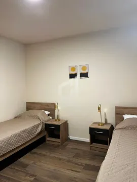 Bedroom with two single beds and nightstands. - image 6
