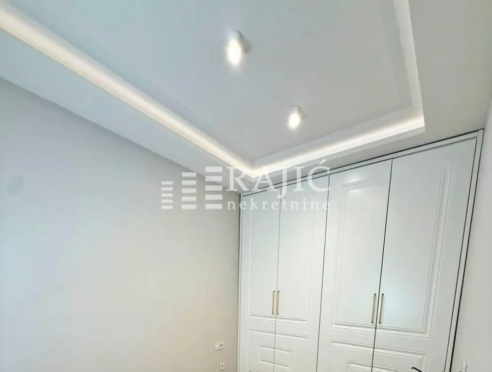 Modern bedroom with a built-in wardrobe and a drop ceiling with lighting.