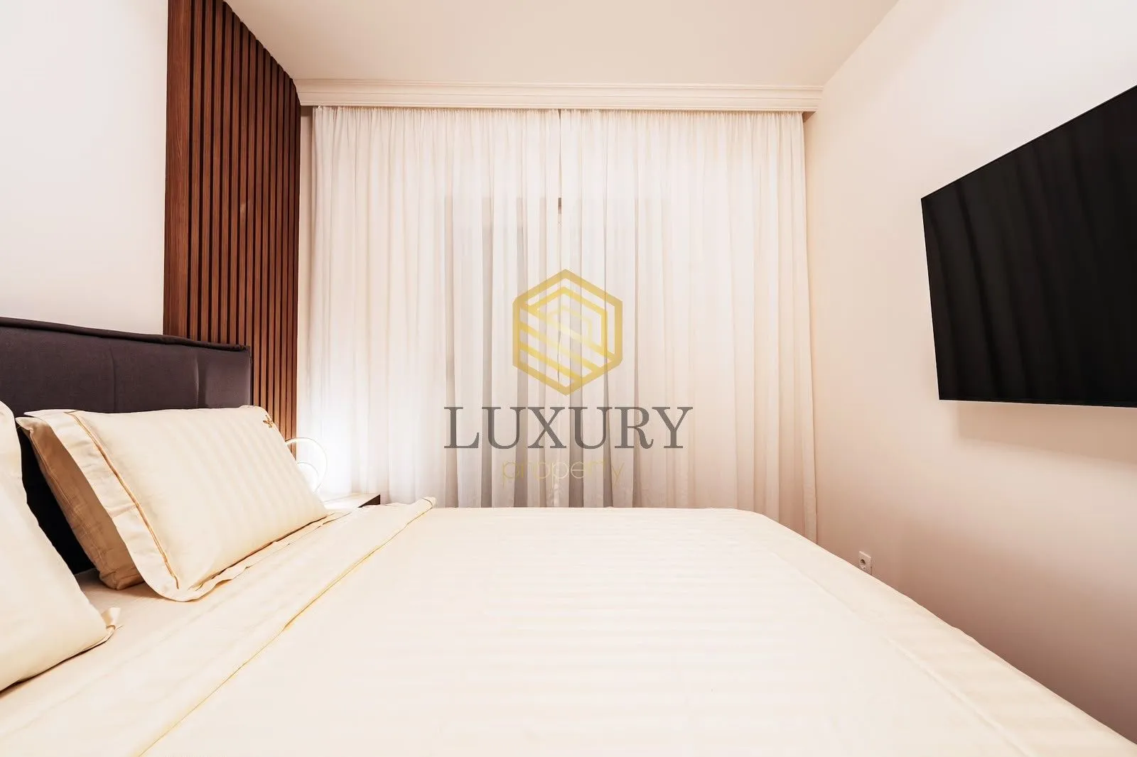 Modern bedroom with a double bed and a wall-mounted TV.
