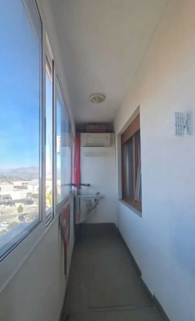 Zastakljeni balkon sa pogledom na grad.