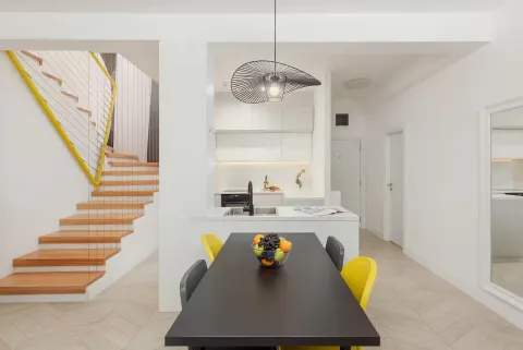 Dining area with a modern kitchen and stairs in the background. - image 6