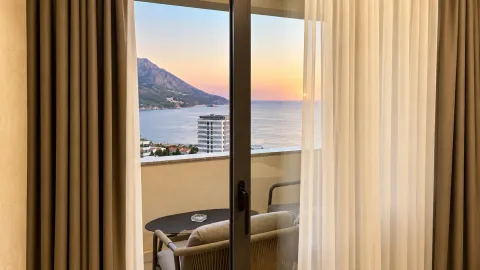 Sea and mountain view through balcony doors with outdoor seating. - image 4