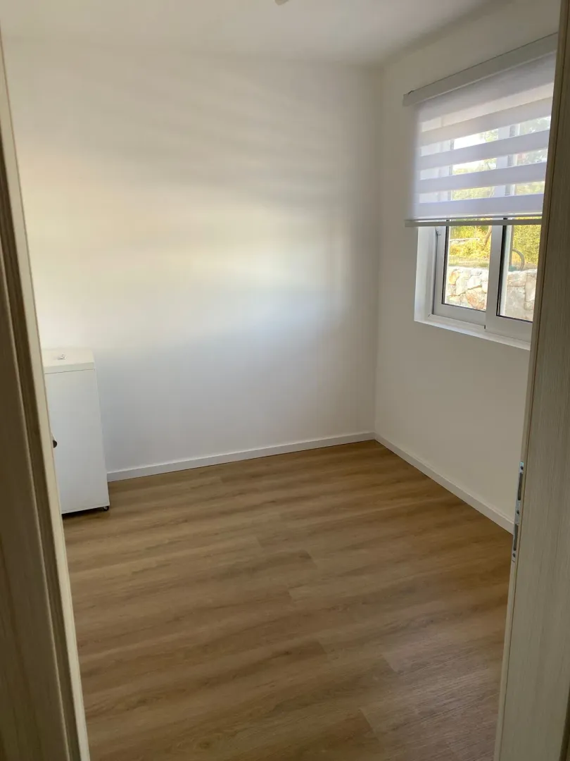 Empty bright room with wooden flooring and a window.