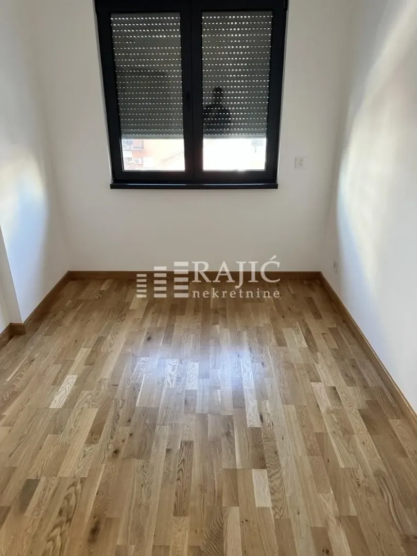 Empty room with parquet flooring and a window.