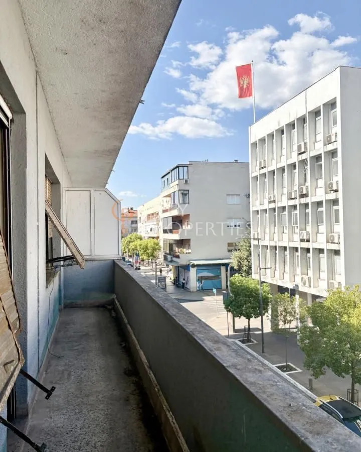 Dugi balkon sa pogledom na ulicu i okolne zgrade.