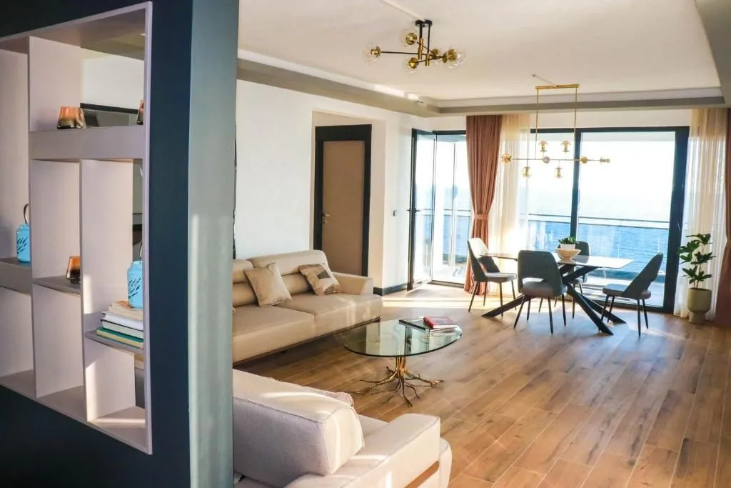 Spacious living room with a sofa set and dining area, with access to a terrace overlooking the sea.