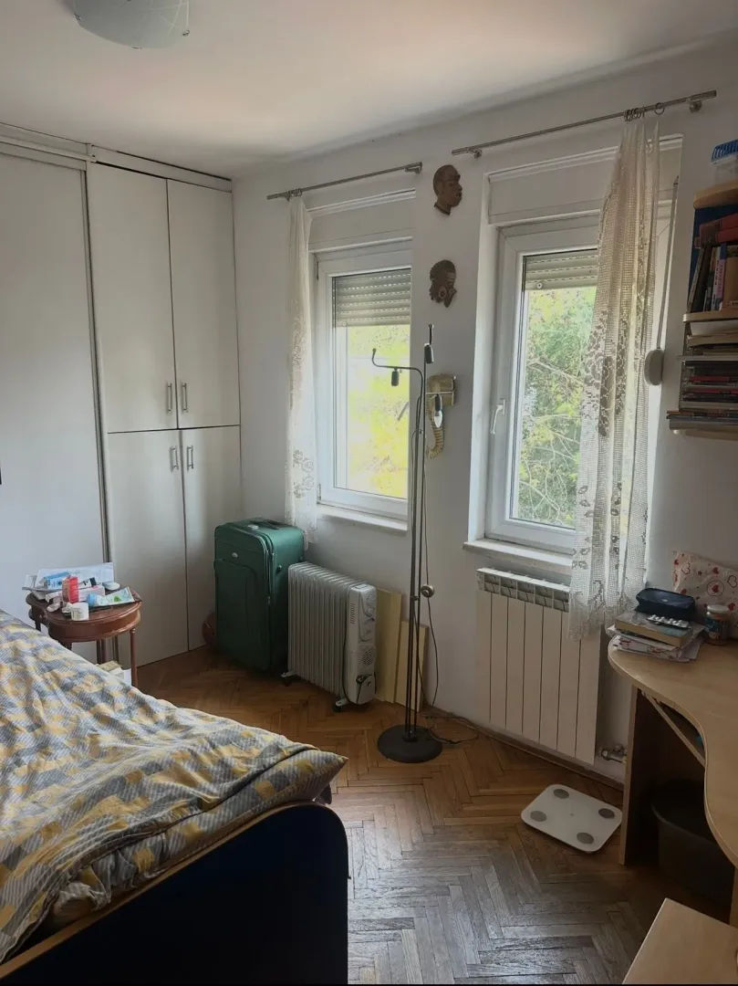 Namještena spavaća soba sa krevetom, plakarom i prozorima.