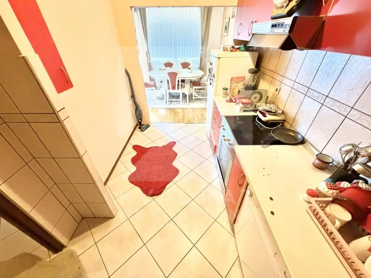 Manja kuhinja sa radnim elementima i aparatom za domaćinstvo.