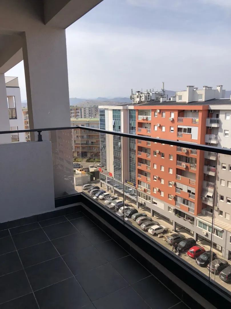 View from the balcony overlooking neighboring buildings and a parking lot.