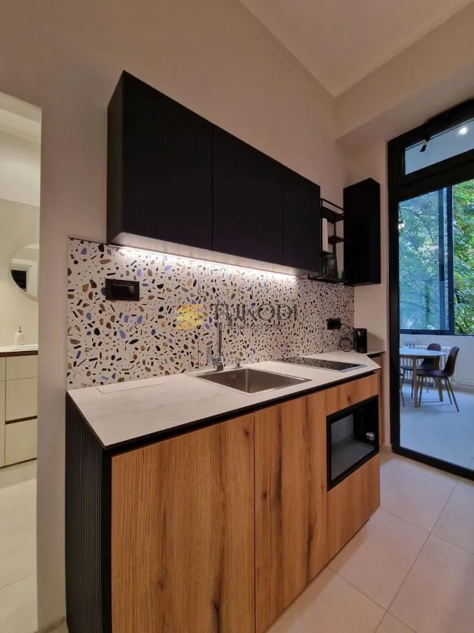 Modern kitchen with wooden lower cabinets, black upper cabinets, and a patterned backsplash.