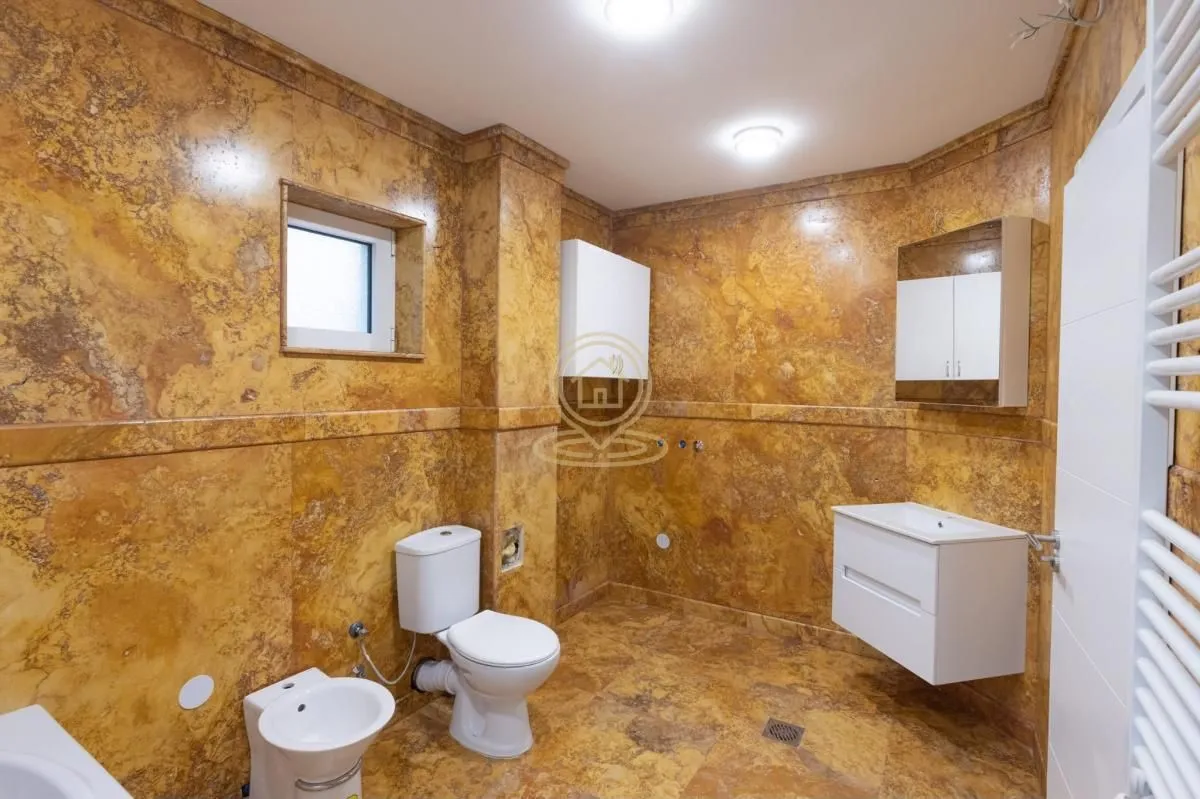 Marble-clad bathroom with white sanitary ware and a window.