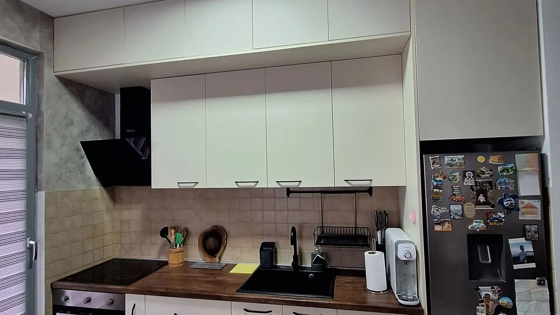 Modern kitchen with white cabinets, dark countertop, and refrigerator.