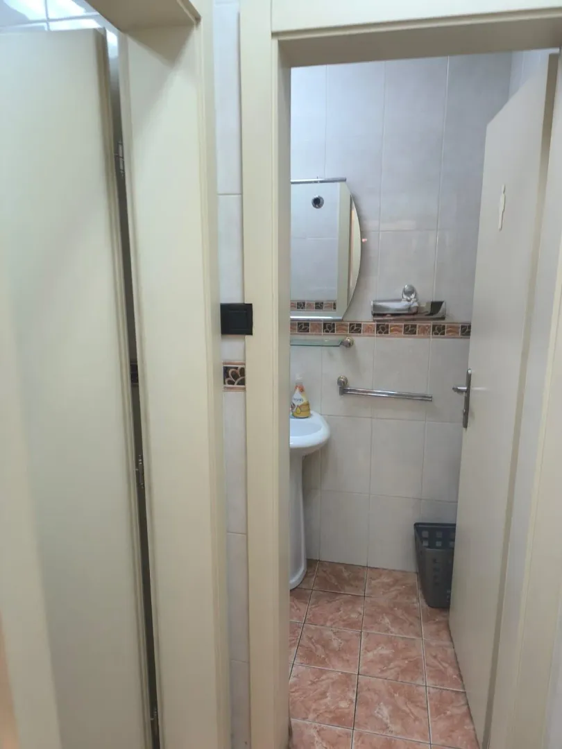 View from the hallway into a small bathroom with a sink and mirror.